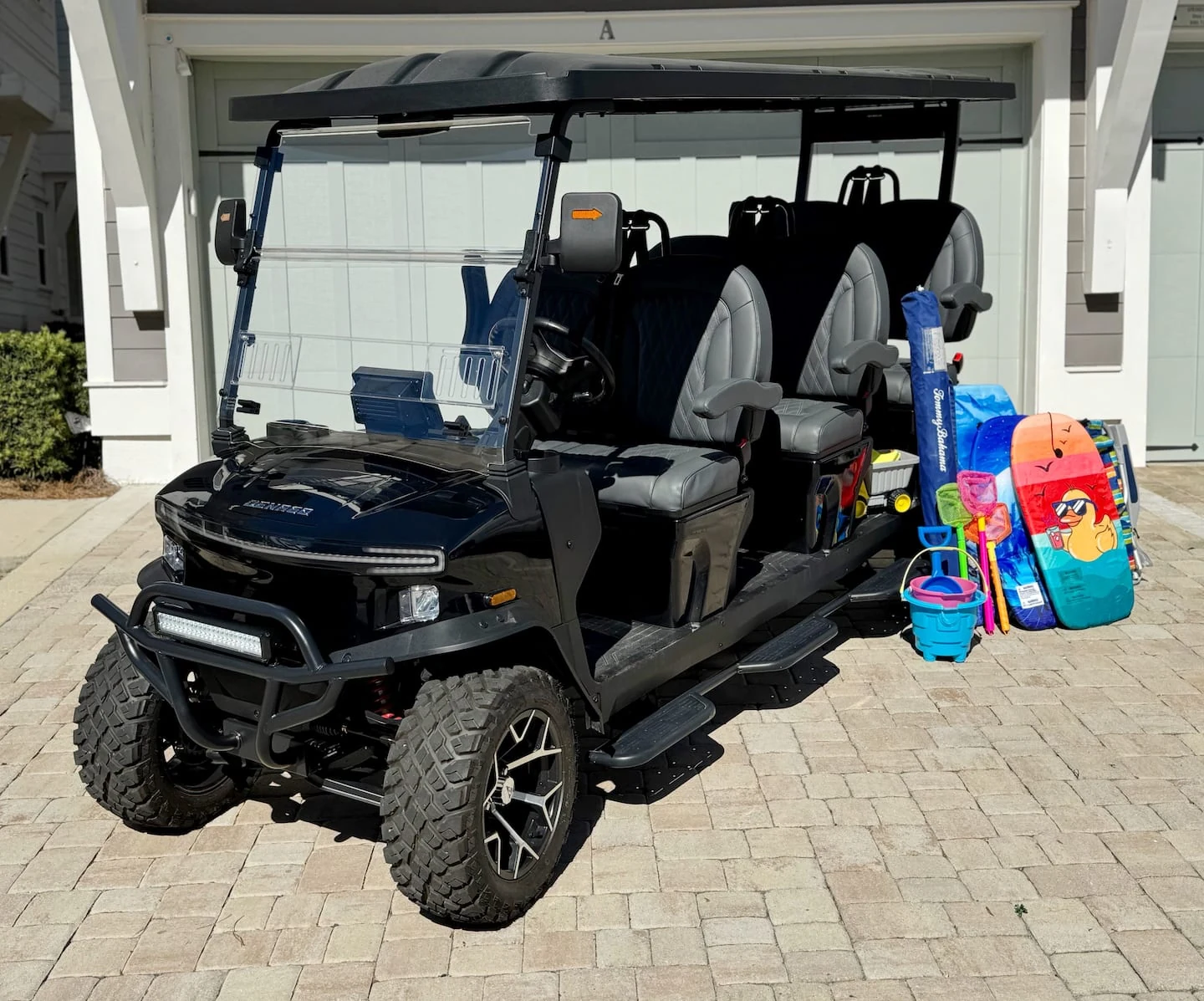 Six-seater golf cart outside the garage with beach gear